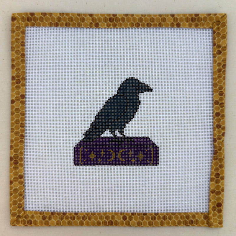 Hand-painted needlepoint canvas of a black raven perched on a purple spellbook
